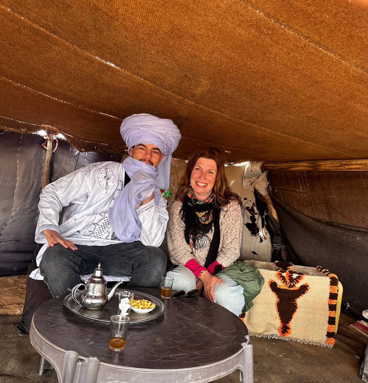 Traveler enjoying traditional Moroccan tea with a nomad family in the Sahara Desert, a cultural highlight of a 10 Day Itinerary Morocco featuring authentic Berber hospitality and desert traditions
